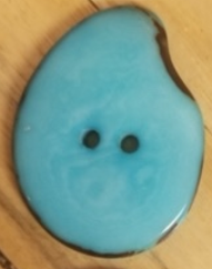 Aqua Hand dyed Tagua Nut Button. Tagua is a sustainably sourced crop also known as vegetable ivory. Sourcing does not cause harm to the rainforests or any animals. Fair Trade Imported.